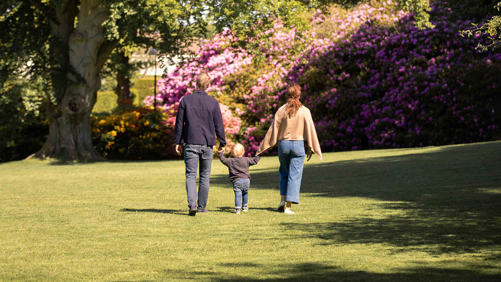 Familj promenerar i trädgården.